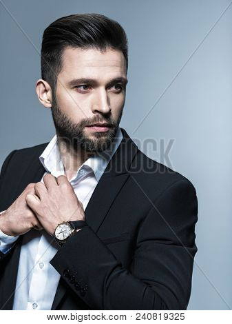 Handsome Man In Black Suit With White Shirt Posing At Studio
