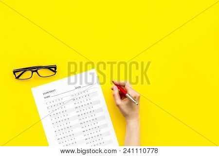 Take The Exam, Write The Exam. Hand With Pen Near Exam Paper On Yellow Background Top View.