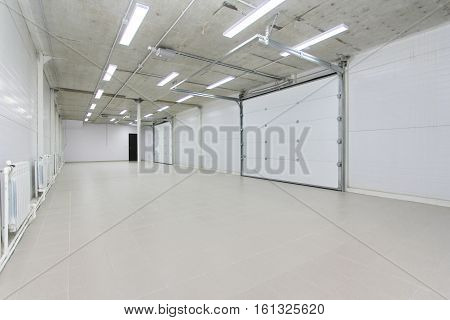 Empty Parking Garage, Warehouse Interior With Large White Gates And Gray Tile Floor