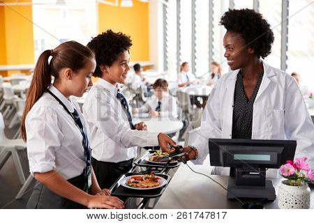 High School Students Wearing Uniform Paying For Meal In Cafeteria