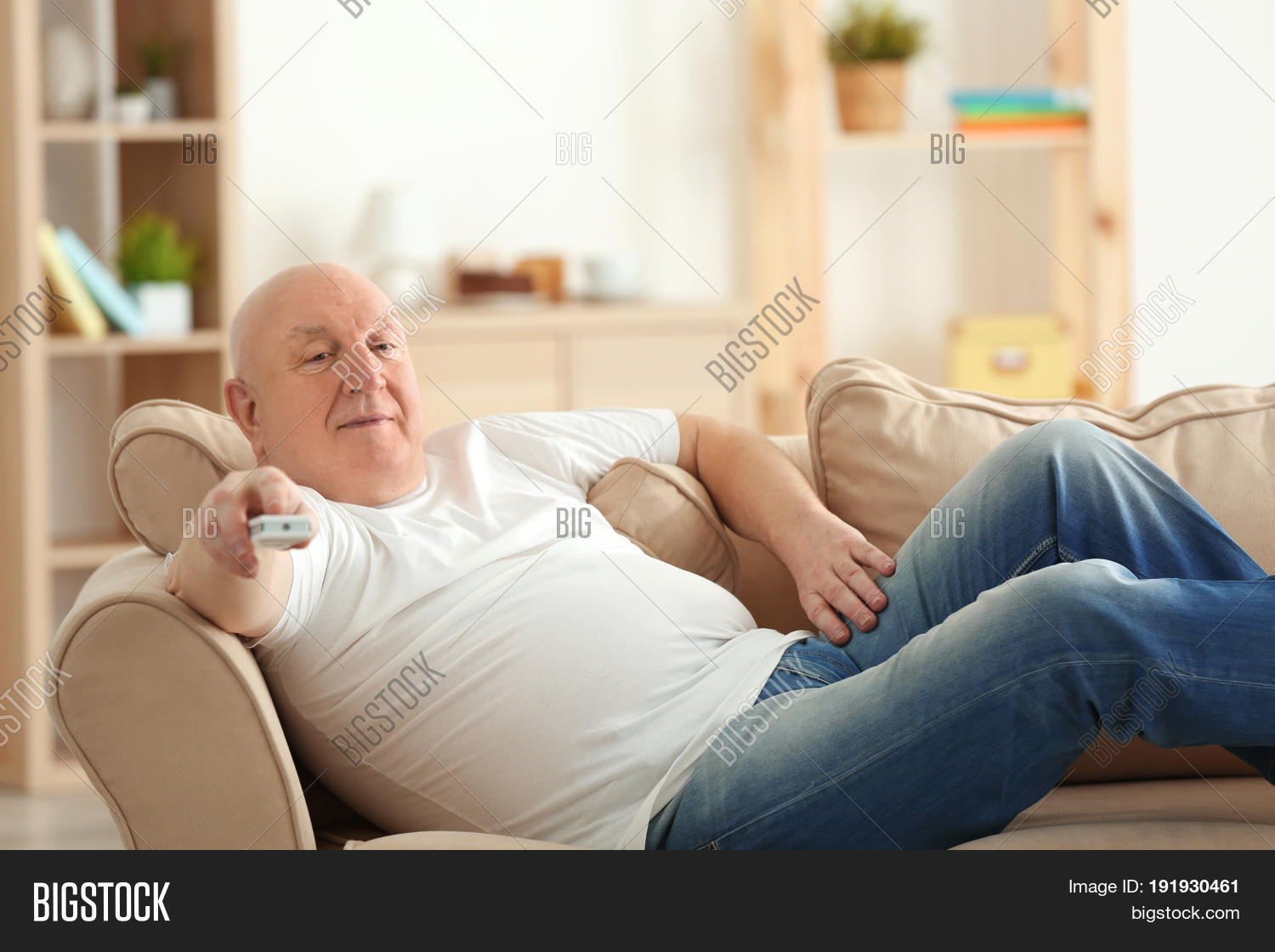 Fat Senior Man Watching Tv While Lying On Sofa At Home