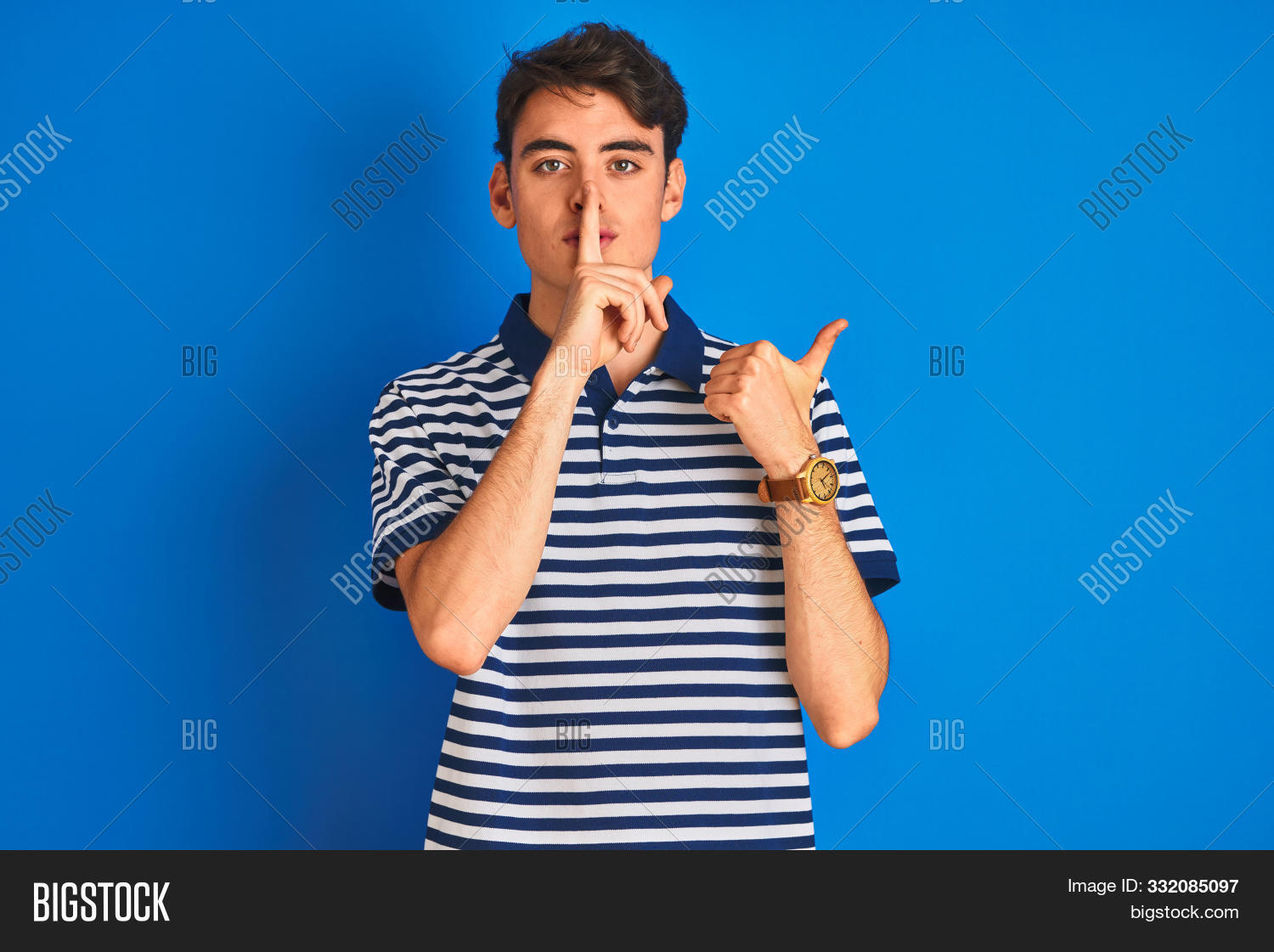 ad,advertisement,asking,attractive,background,blue,boy,calm,casual,caucasian,confident,expression,fashion,finger,gesture,gesturing,guy,hand,handsome,isolated,lips,looking,male,man,minor,mouth,mute,pointing,portrait,pose,quiet,relax,secret,shh,shushing,shut,side,sign,silence,silent,standing,stop,studio,t-shirt,teen,teenager,up,young