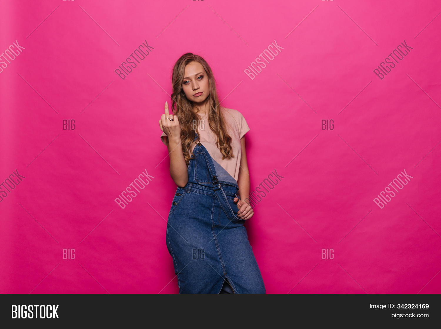 actor,adult,aggression,anger,attractive,background,bad,beautiful,beauty,caucasian,cheerful,concept,copyspace,denim,emotion,expression,face,fashion,female,finger,gesture,girl,hand,happy,isolated,joyful,laughing,lifestyle,middle,obscene,offensive,one,person,pink,portrait,provocation,provocative,rude,showing,sign,smile,smiling,standing,studio,surprise,symbol,woman,young