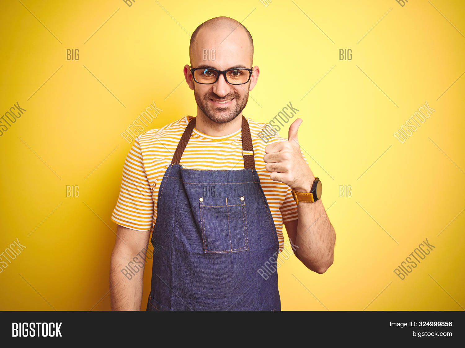 adult,approve,approving,apron,baker,bald,barista,bartender,beard,cheerful,confident,cook,doing,gesture,glasses,happy,like,looking,male,ok,okay,portrait,positive,professional,restaurant,right,shop,showing,sign,smile,smiling,stand,success,successful,teeth,thumb,thumbs,thumbs up,trust,uniform,up,winner,yellow,young