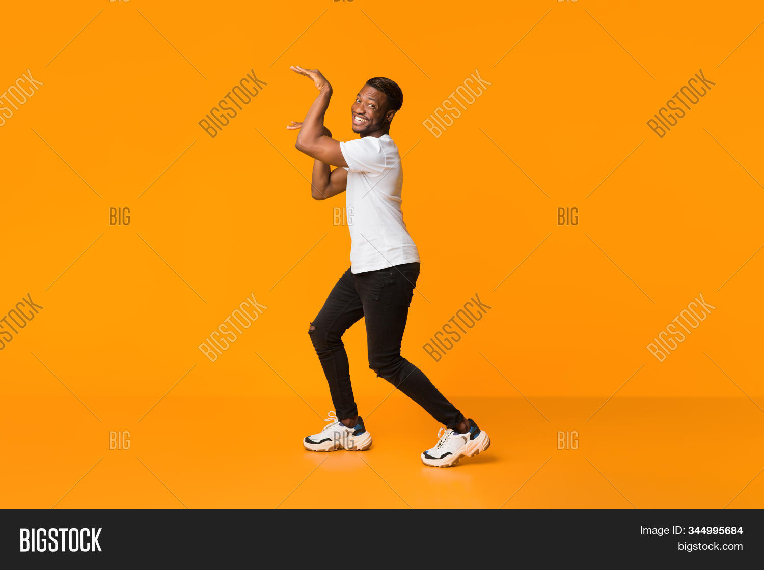 comic,adult,fool,toothy,carefree,funny,smiling,dancing,positive,fun,emotion,man,masculine,banner,background,activity,millennial,egyptian,young,guy,excited,male,casual,orange,happy,joy,black,t-shirt,egypt,stylish,style,silly,entertaining,30s,pose,20s,hands,studio,ad,afro,advertisement,concept,people,person