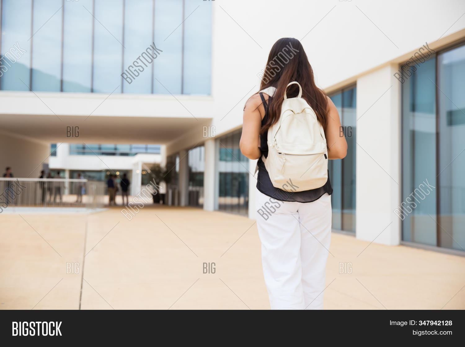 person,woman,female,young,adult,youth,asian,beautiful,attractive,pretty,casual,clothing,outdoors,outside,street,student,college,university,education,educational,holding,concept,standing,day,walk,walking,wearing,backpack,bag,building,brunette,study,learn,learning,daytime,daylight,urban,architecture,city,campus