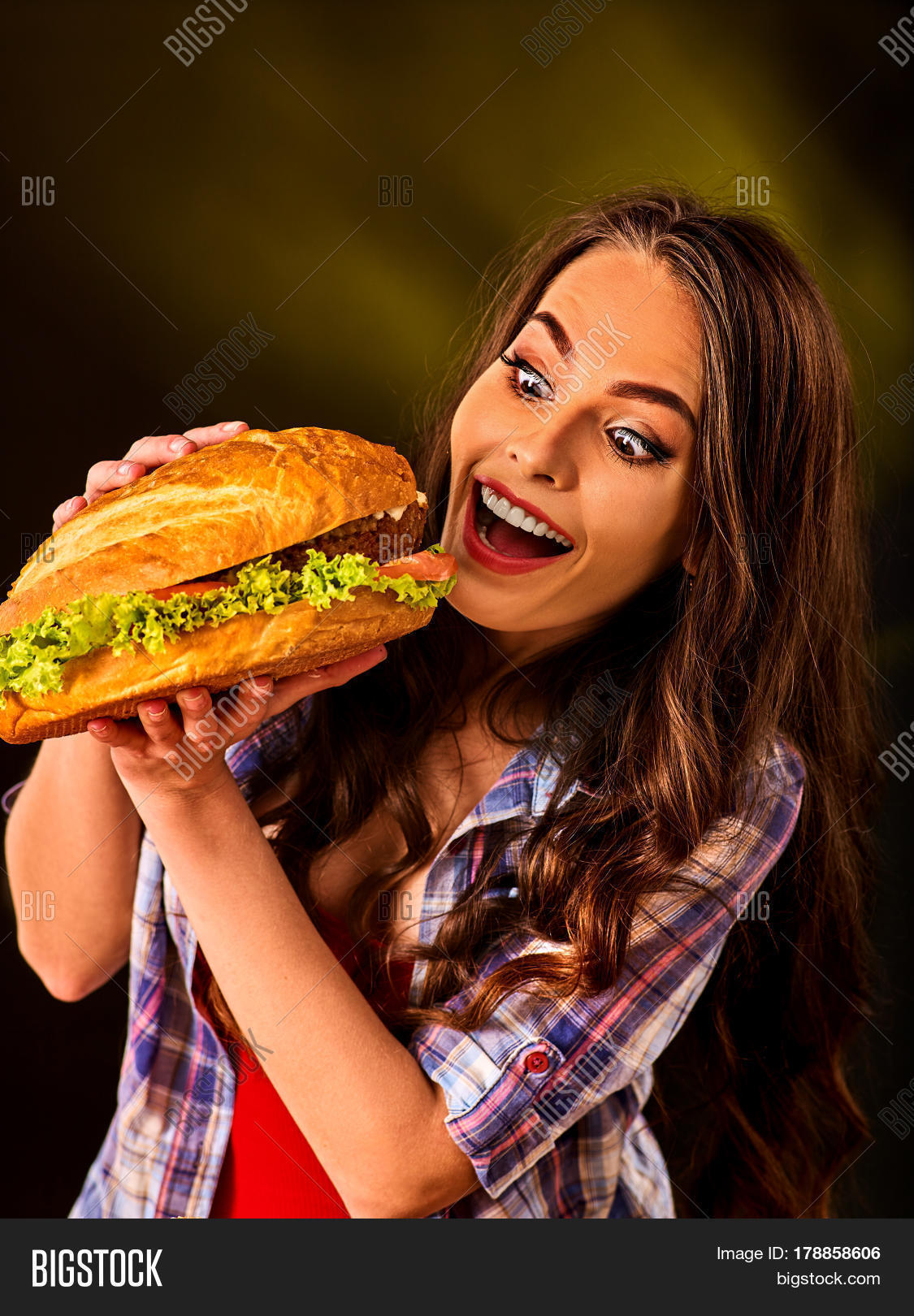 Woman eating hamburger. Student consume fast food. Girl bite of very