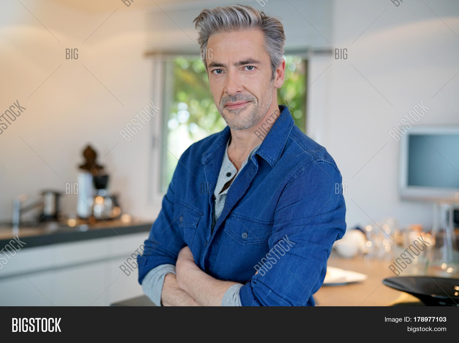 40s,45-50 years old,50s,adult,attractive,casual,confident,contemporary,european,grey hair,guy,handsome,home,indoor,inside,kitchen,lifestyle,man,mature,middle-aged,modern house,one,people,relaxed,smart,smiling,standing
