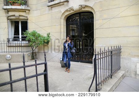 Chinese Gladden Girl Leaving University Building With Big Valise And Speaking By Smartphone In  . Co