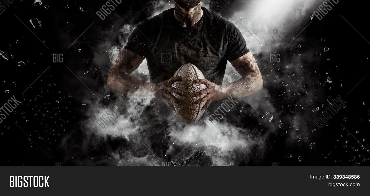 action,activity,aggression,arena,athlete,background,ball,banner,black,brave,competitive,dark,event,field,floodlight,football,game,goal,handsome,healthy,hero,hit,jump,kick,lawn,male,man,match,mud,muscular,outdoors,player,playing,professional,rugby,sky,smoke,sport,sportsman,stadium,team